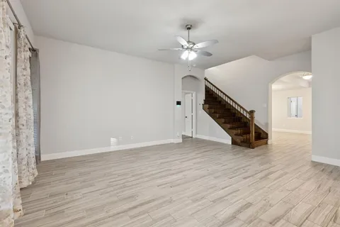 a view of an empty room with wooden floor and stairs