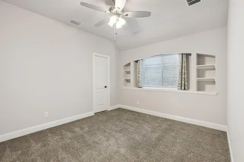 an empty room with chandelier fan and windows