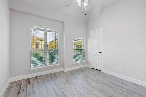 an empty room with wooden floor and windows