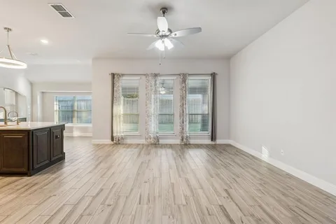 a view of an empty room with a kitchen and wooden floor