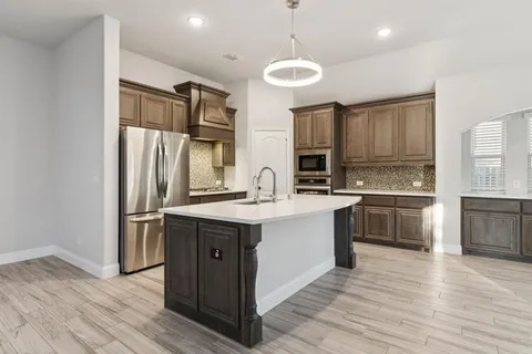 a kitchen with stainless steel appliances granite countertop a refrigerator a sink dishwasher a stove and white countertops with wooden floor