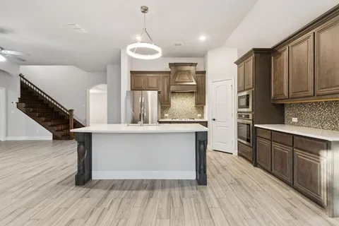 a kitchen with stainless steel appliances granite countertop a sink a stove and oven with wooden floor