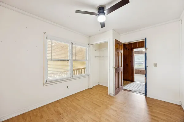 a view of an empty room with wooden floor and a window