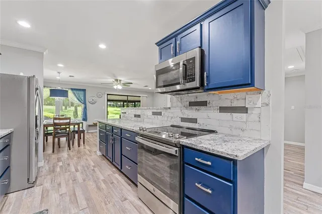 a kitchen with stainless steel appliances granite countertop a stove top oven a sink dishwasher a dining table and chairs with wooden floor