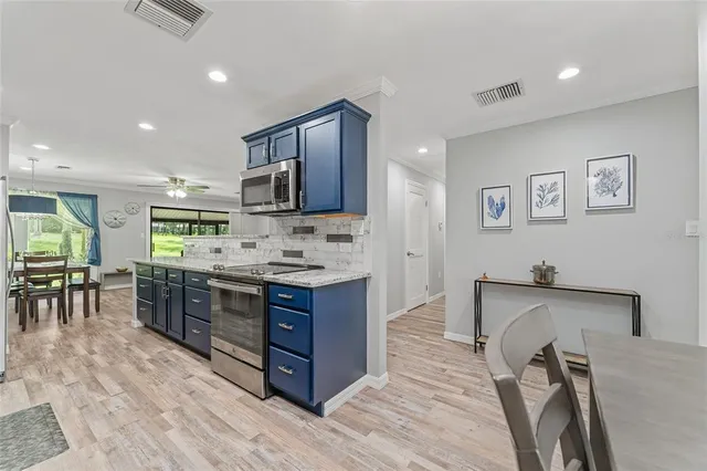 a kitchen with stainless steel appliances kitchen island granite countertop a stove refrigerator and cabinets