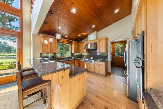 a view of a kitchen with kitchen island granite countertop wooden floor and stainless steel appliances
