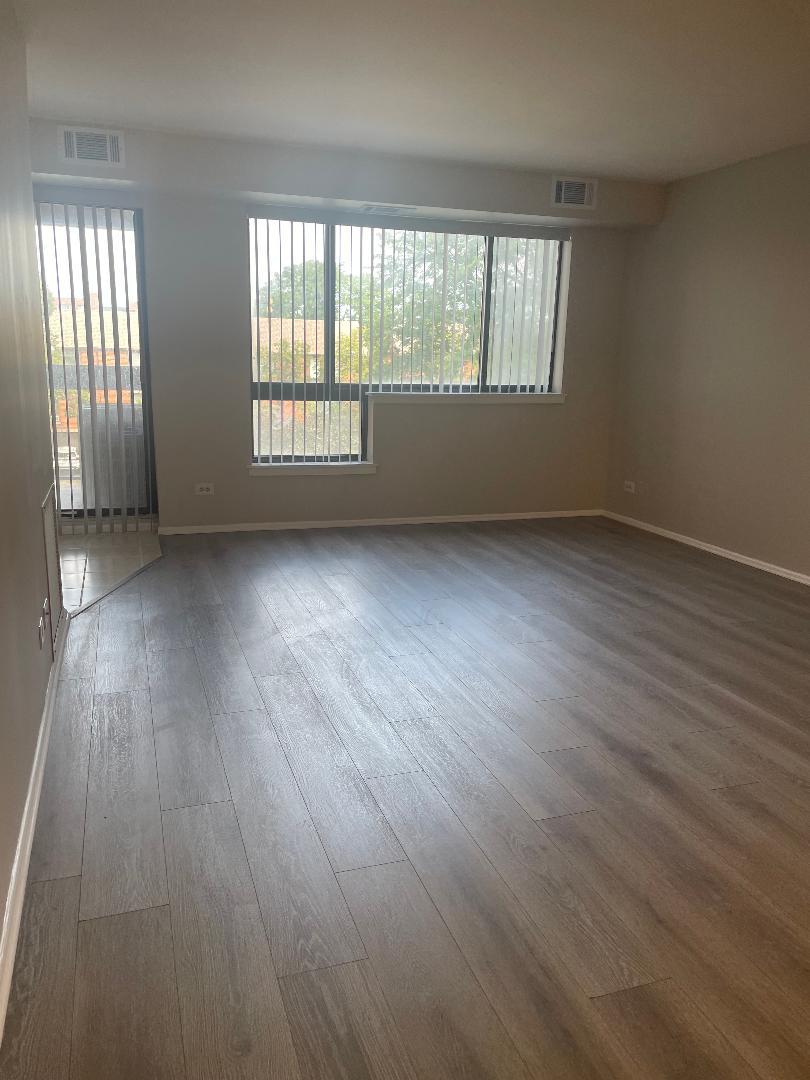 3801 Appian Way, Unit 302 Glenview, IL 60025 - Photo 3 of 16 an empty room with wooden floor and windows