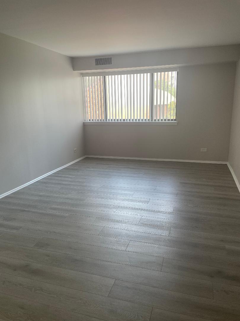 3801 Appian Way, Unit 302 Glenview, IL 60025 - Photo 8 of 16 an empty room with wooden floor and windows
