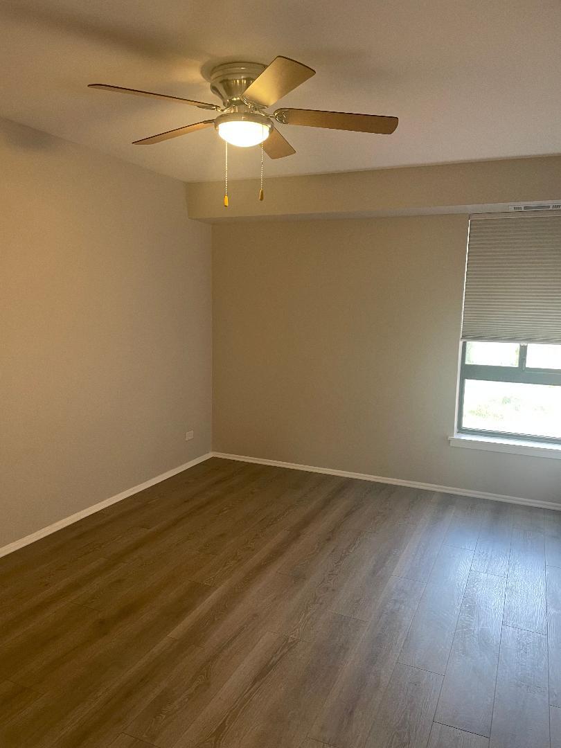 3801 Appian Way, Unit 302 Glenview, IL 60025 - Photo 10 of 16 an empty room with wooden floor fan and windows