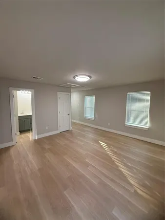 a view of an empty room with window and wooden floor