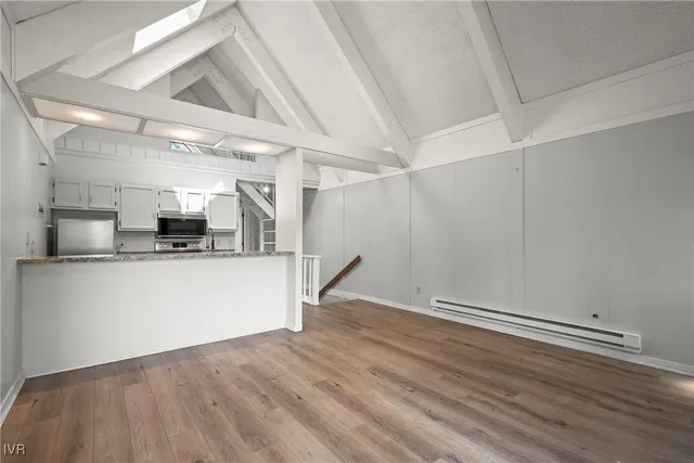 a view of kitchen and empty room with wooden floor