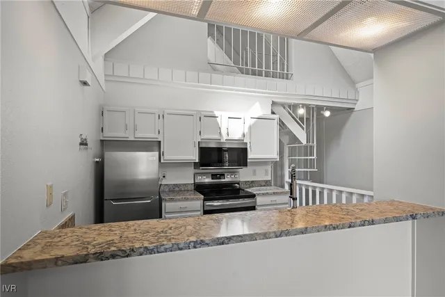 a kitchen with granite countertop a refrigerator and a stove top oven