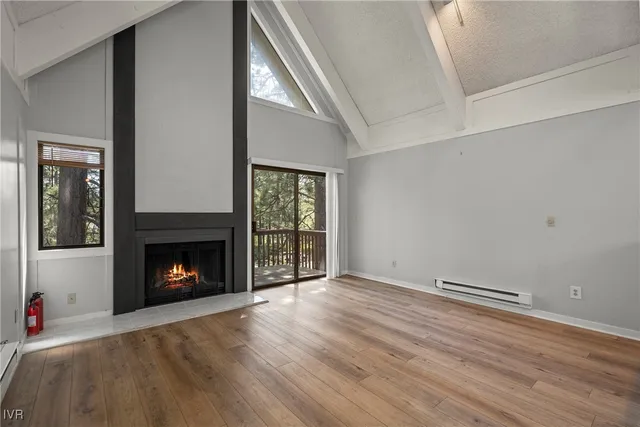 a view of an empty room with wooden floor fireplace and a window