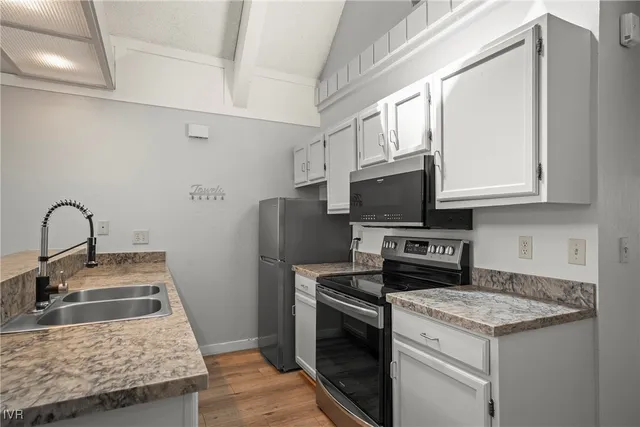 a kitchen with stainless steel appliances granite countertop a stove top oven a sink and a microwave