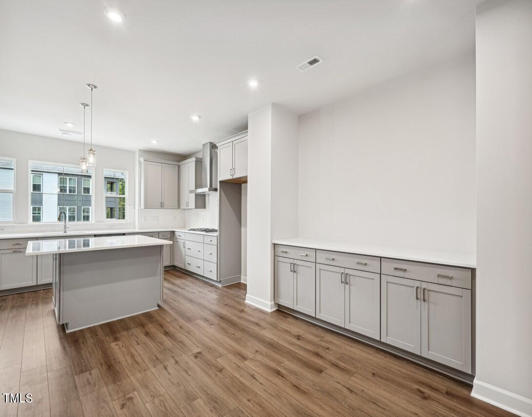 4816 Cypress Tree Lane Raleigh, NC 27612 - Photo 7 of 15 a large white kitchen with granite countertop a stove top oven a sink and dishwasher with wooden floor