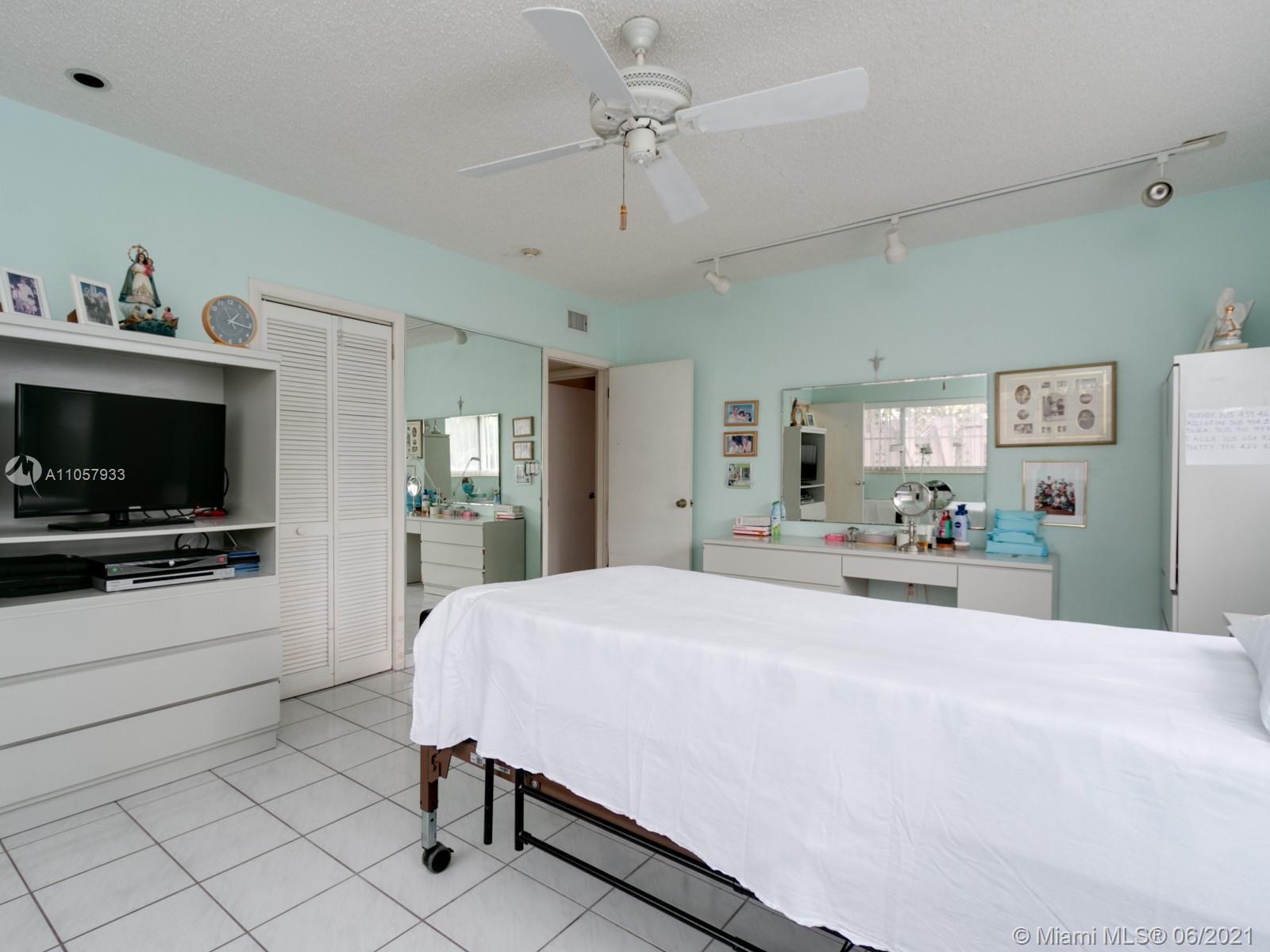 4708 Alton Road Miami Beach, FL 33140 - Photo 11 of 38 a large bedroom with a bed and a flat screen tv