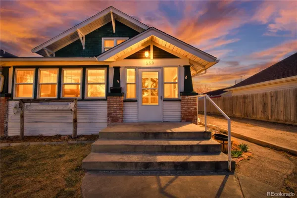 a front view of a house with wooden stairs and a bench