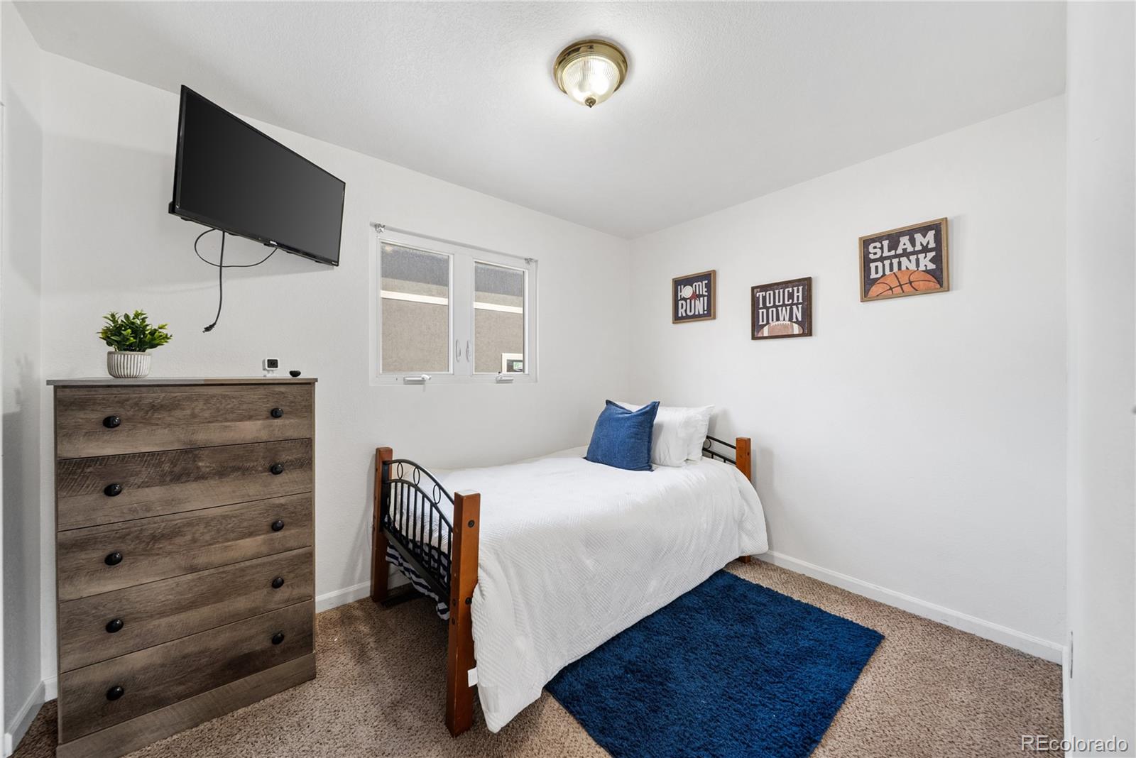 550 Custer Avenue Akron, CO 80720 - Photo 21 of 35 a bedroom with a bed and a flat screen tv