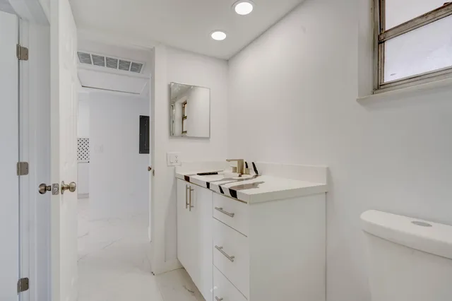a bathroom with a granite countertop sink a toilet and a mirror