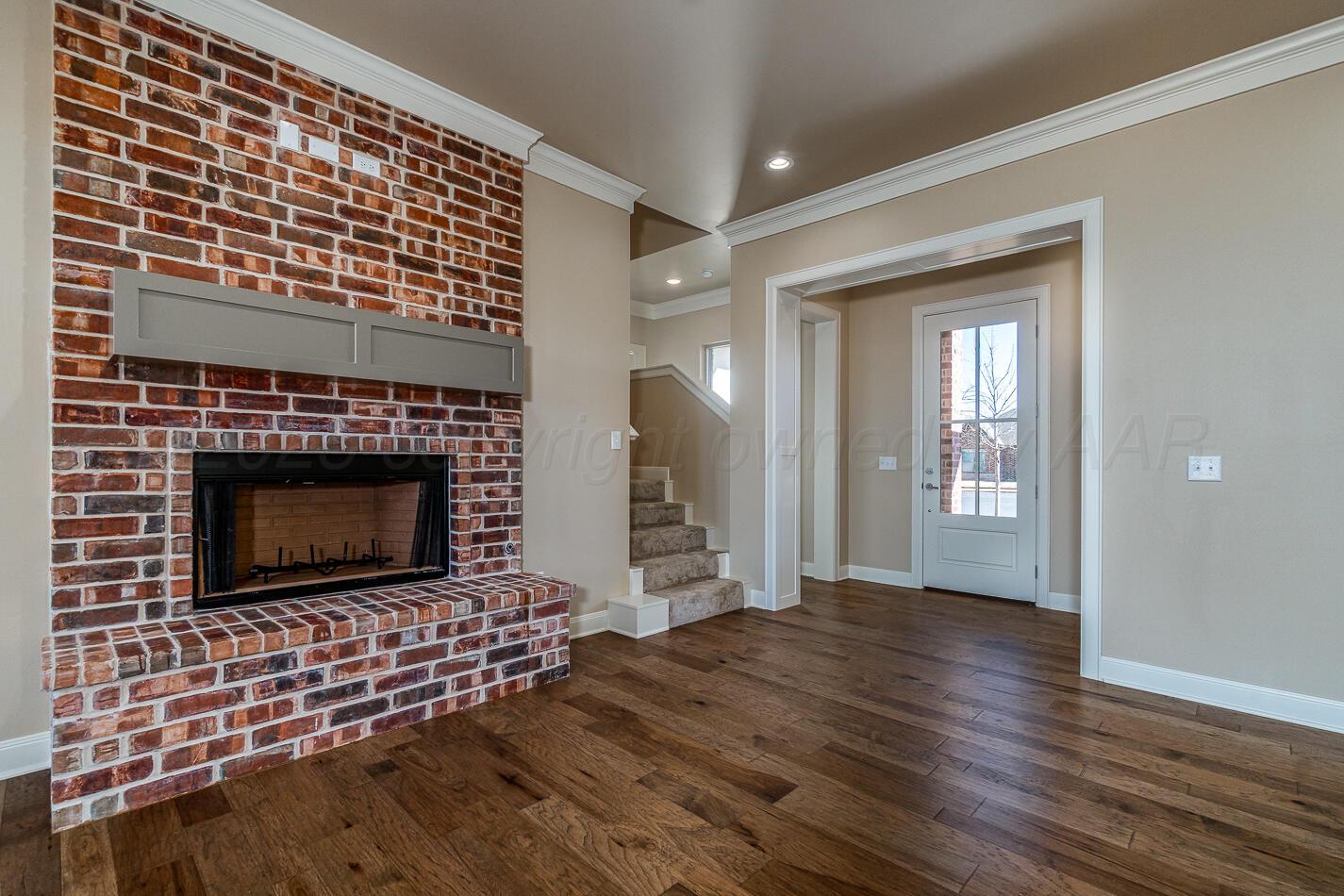6304 Lauren Ashleigh Drive Amarillo, TX 79119 - Photo 4 of 38 a living room with a fireplace and a wooden floor
