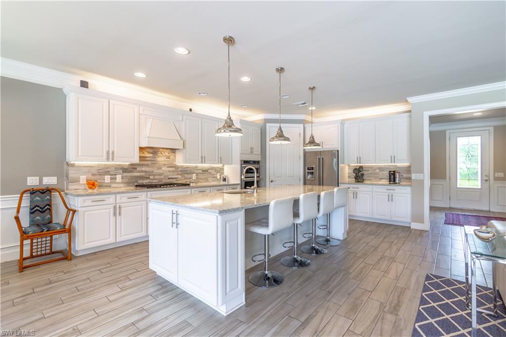 7247 Clamshell Lane Naples, FL 34114 - Photo 11 of 33 a kitchen with white cabinets and stainless steel appliances