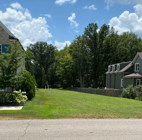 a view of a house with a big yard and potted plants and large trees