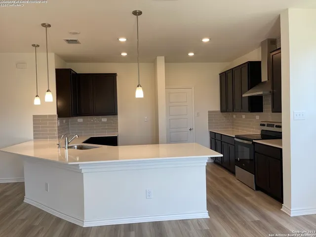 a kitchen with kitchen island granite countertop a sink and a stove top oven with wooden floor