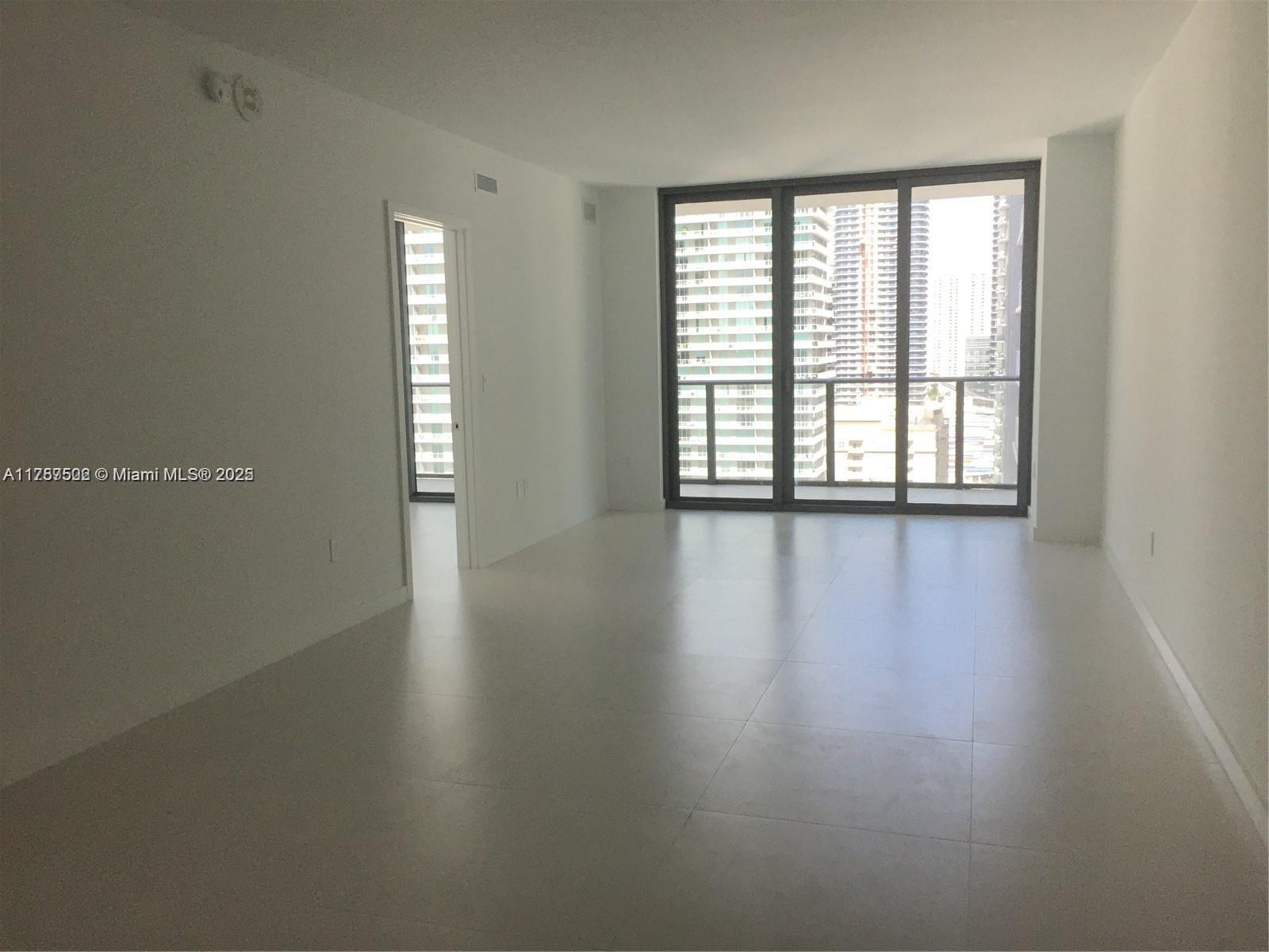 1300 South Miami Avenue, Unit 1910 Miami, FL 33130 - Photo 6 of 14 an empty room with wooden floor and windows with curtains