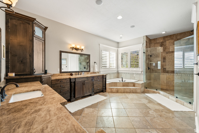 1205 North Elk Rdg Lane, Unit 202 Alpine, UT 84004 - Photo 29 of 88 Spacious bathroom featuring natural stone flooring, a corner soaking tub with stepped surround, a glass-enclosed shower with natural stone tile, and dark wood vanities with integrated sinks and stone countertops
