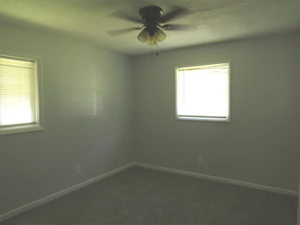 an empty room with a window and a fan