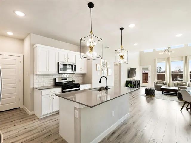 a kitchen with stainless steel appliances granite countertop a sink a stove and a wooden floor