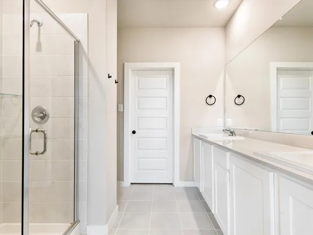 a bathroom with a granite countertop sink two mirror and shower
