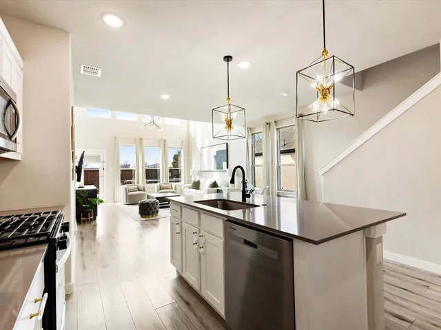 a kitchen with sink a center island stainless steel appliances and living room view