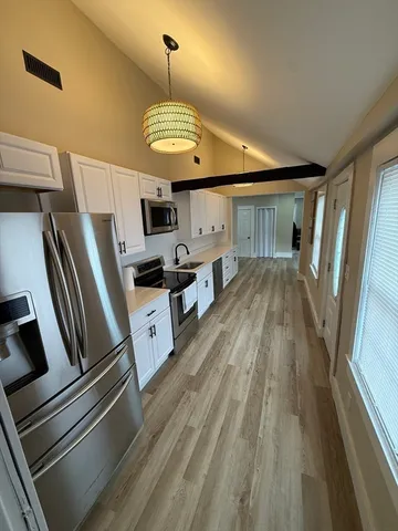 a open kitchen with stainless steel appliances granite countertop a stove oven a refrigerator and a fireplace with wooden floor