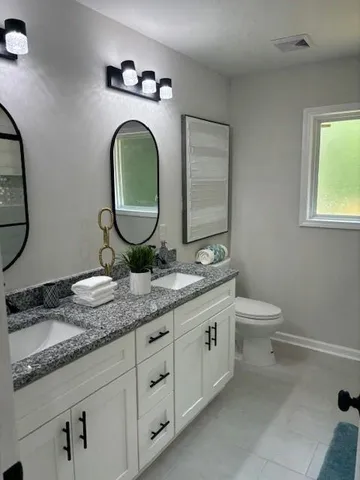 a bathroom with a granite countertop toilet sink and mirror