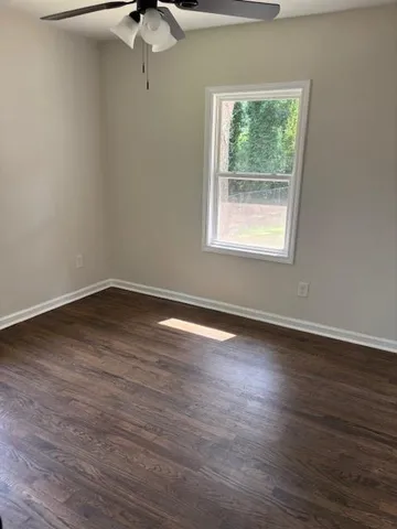 a view of a room with wooden floor chandelier fan and window