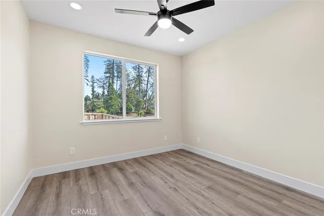 an empty room with wooden floor ceiling fan and windows