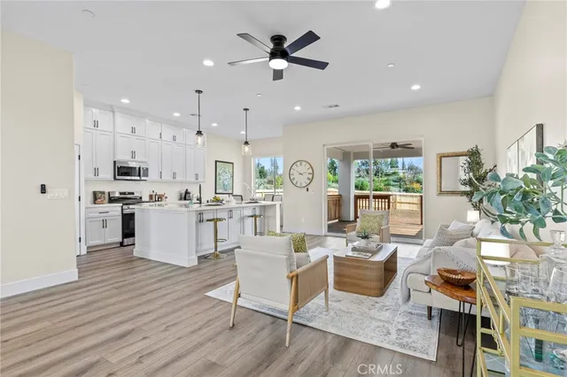 a living room with furniture kitchen area and a wooden floor