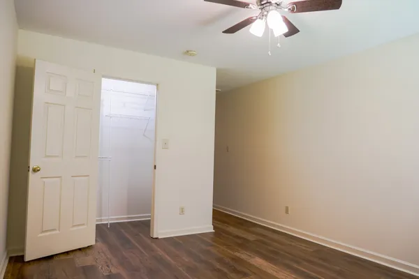an empty room with wooden floor closet and windows
