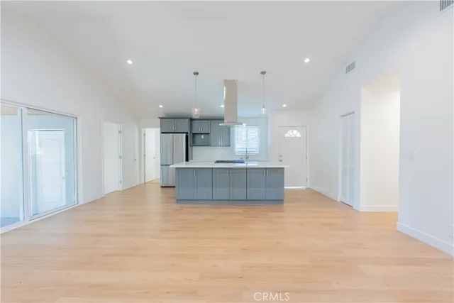 a large kitchen with a large counter top a sink stainless steel appliances and cabinets