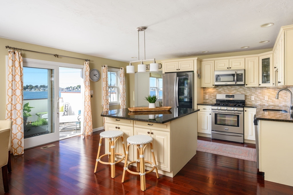 76 Wyola Road Hull, MA 02045 - Photo 2 of 28 a large kitchen with stainless steel appliances a stove a sink dishwasher a microwave oven and a dining table with wooden floor