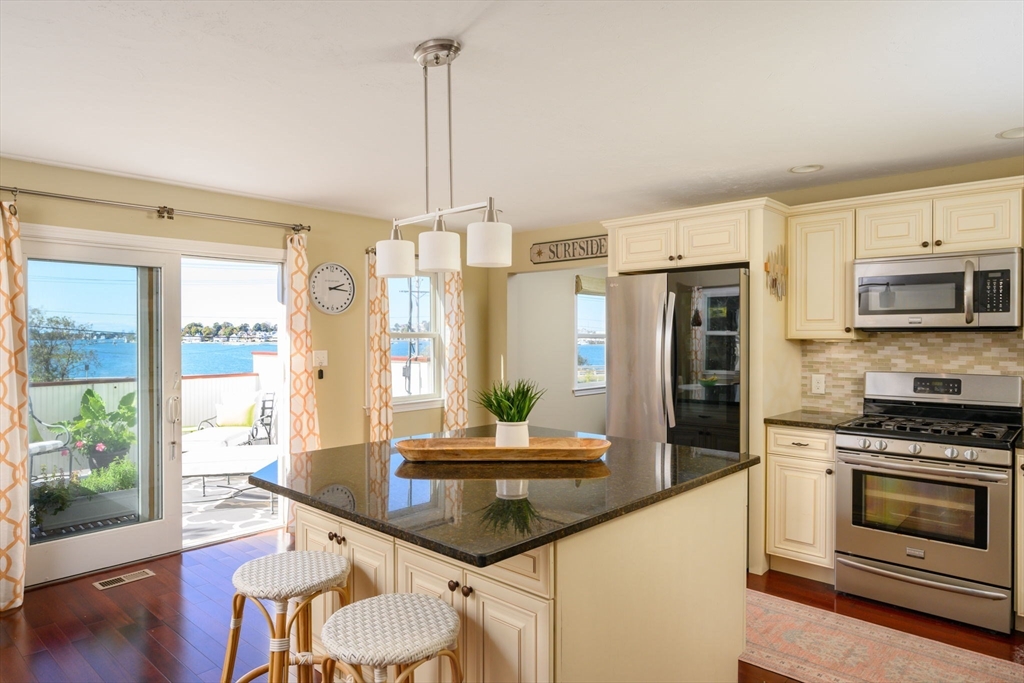 76 Wyola Road Hull, MA 02045 - Photo 28 of 28 a kitchen with stainless steel appliances kitchen island granite countertop a refrigerator a stove and a wooden floors