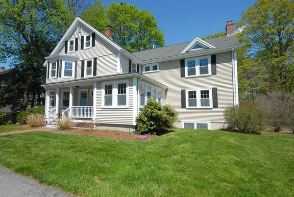 a front view of a house with a yard and trees