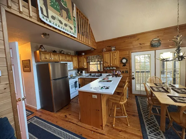 a view of a kitchen with stainless steel appliances granite countertop a stove a refrigerator a dining table and chairs with wooden floor