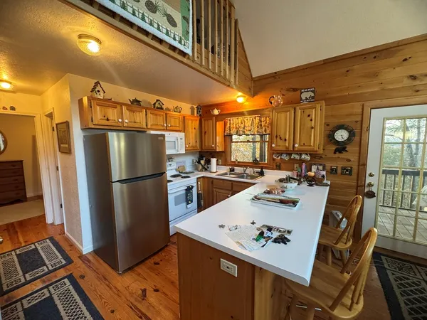 a kitchen with a refrigerator a stove a sink and a dining table with wooden floor