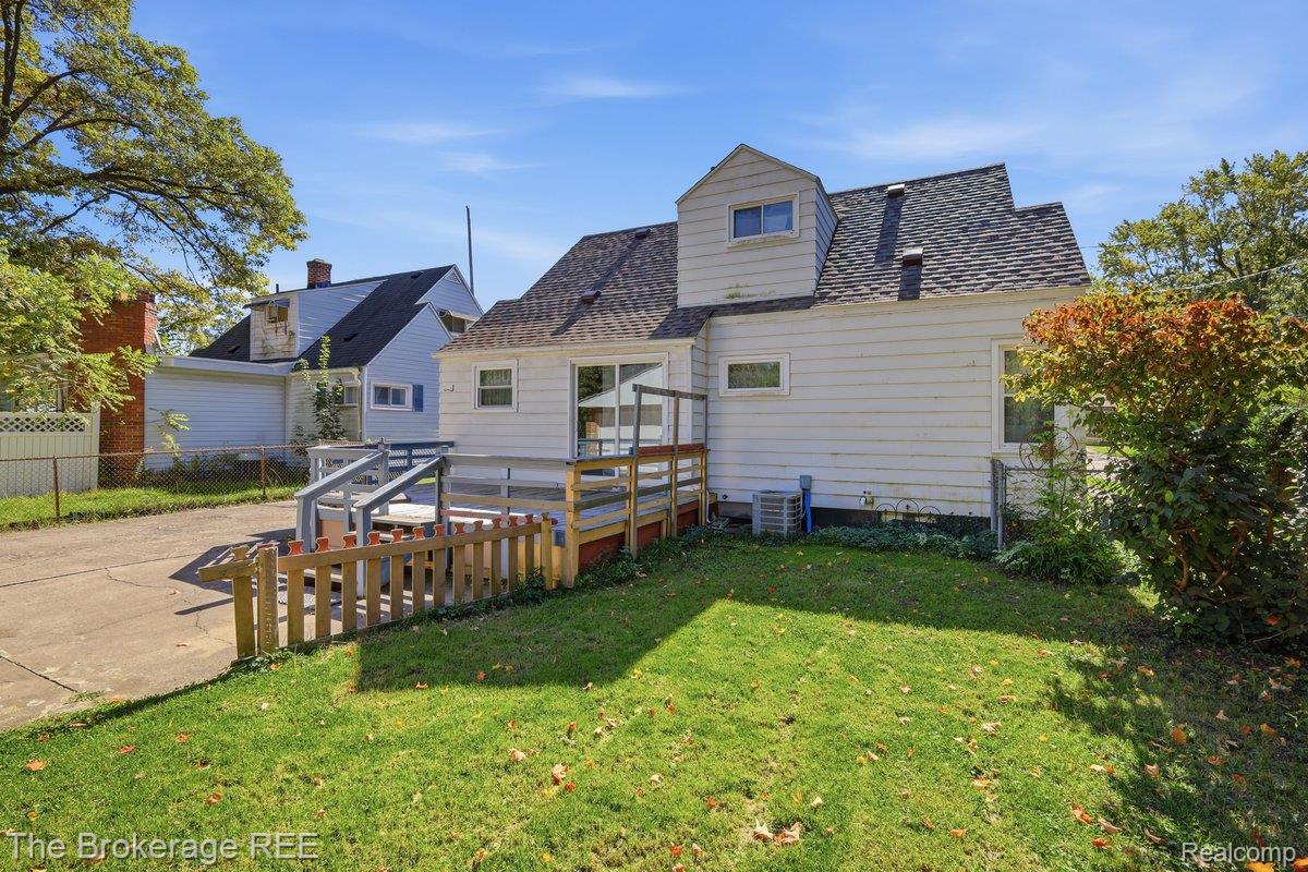 613 East Atherton Road Flint, MI 48507 - Photo 36 of 42 Expansive rear yard with a wooden deck and railing, mature perimeter trees, and a concrete driveway