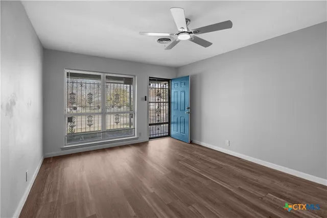 a view of an empty room with a window and wooden floor