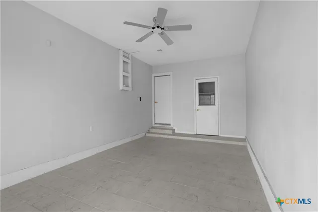 an empty room with a ceiling fan and carpet