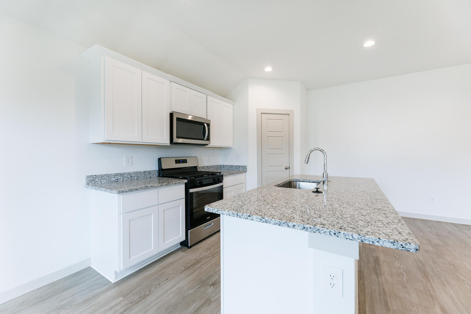 2305 150th Street Lubbock, TX 79423 - Photo 14 of 39 a kitchen with granite countertop a sink and a stove top oven with wooden floor
