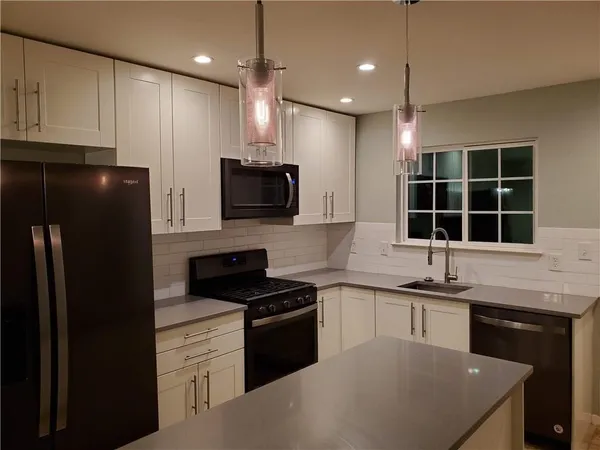 a kitchen with stainless steel appliances granite countertop a sink a stove a refrigerator and cabinets